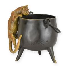 Bronzen sculptuur van klimmende kat bij donkere ketel