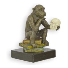 Bronzen beeld van Darwin-aap met schedel op kleurrijke boeken